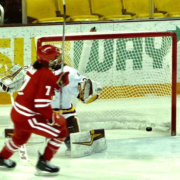 As the puck dropped from the upper left corner, Wisconsin’s Sam Cogan celebrated scoring the only goal of an eight-skater shootout against UMD goaltender Jessica Convery. Photo credit: John Gilbert