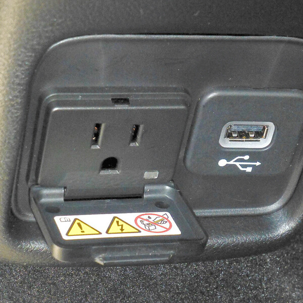 On the lower back of the center console, two electrical outputs include one for a household  plug-in, are accessible from rear seats. Photo credit: John Gilbert