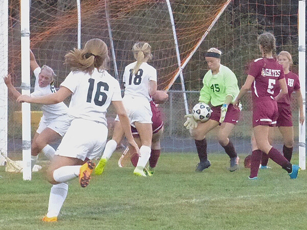 Two Harbors goalkeeper Callie Bergeron somehow survived the close-in attack by Cloquet-Carlton scoring stars Kendra Kelley (18) and Kiana Bender (wrapped around goal post at left), although Bender scored two late goals for a 2-1 Lumberjacks victory. Photo credit: John Gilbert