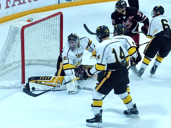 Marshall goaltender Alex Busick stretched to get his toe on a Duluth East shot as East’s Brendan Baker lurked on the far side of the crease. Photo credit: John Gilbert