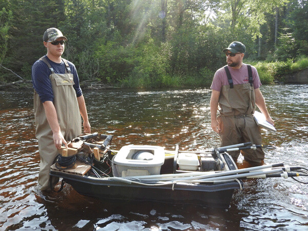 DNR fisheries technician Nathan Klein, and fisheries biologist Max Wolter, explain the electroshocking equipment on their modified boat. Photo by Emily Stone. 