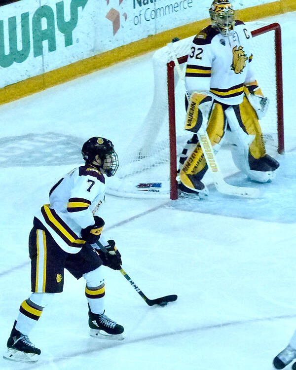 UMD goaltender Hunter Shepard could relax for a moment against Denver as defenseman Scott Perunovich stopped the action while picking out his next assist. Photo credit: John Gilbert