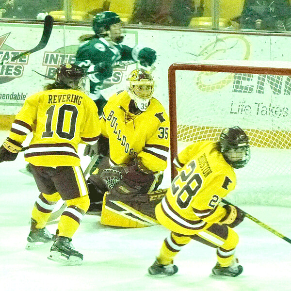 The incomparable Maddie Rooney blocked a shot by Bemidji State"s Abby Halluska (circling behind net) for her 30th save Friday night to secure a 2-0 shutout and give Rooney a program record 3,001 saves for her 4-year UMD career. Photo credit: John Gilbert