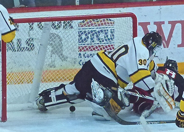 Duluth East's Austin Jouppi (8), who had assisted on two goals, crashed over Marshall's sophomore goaltender Alex Busick after the puck had already gone across the line to give East a 4-1 lead. Photo credit: John Gilbert