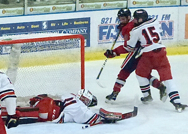  East goaltender Konrad Kausch dived from his crease to smother a shot, while Finn Hoops covered Lakeville North's Caden Smith. Photo credit: John Gilbert