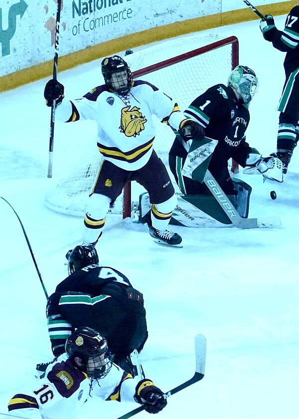  Luke Loheit (16) gained a 1-1 tie for UMD as Jesse Jacques bothered goalie Peter Thome on the goal, but North Dakota scored two late goals to win the second game 3-2. Photo credit: John Gilbert